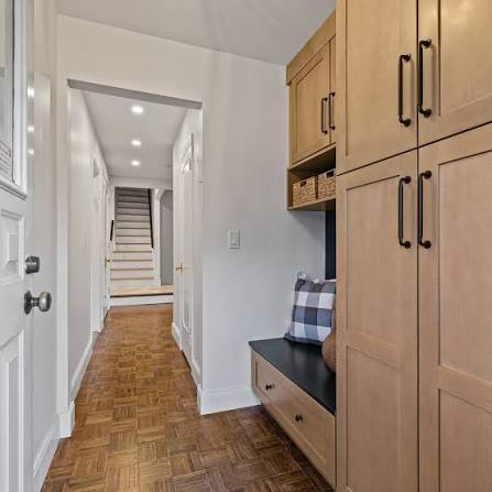 Mudroom entry with light wood lockers, a bench with a plaid cushion and woven storage baskets