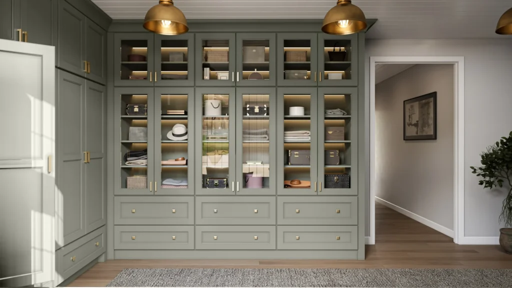 Sage green built-in wardrobe with glass-front doors, open shelving and brass dome lights