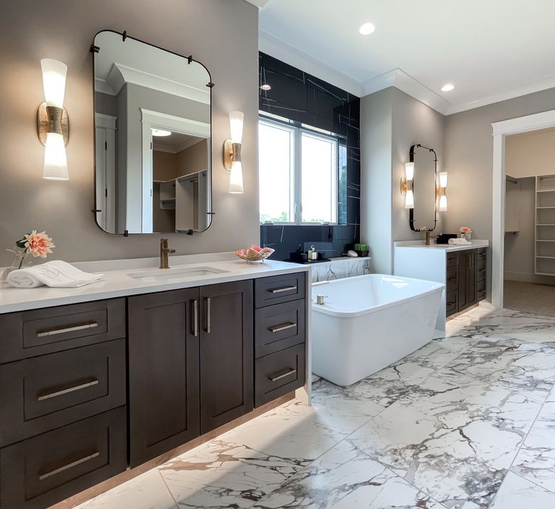 Primary bathroom with dark espresso double vanity, freestanding soaking tub and marble-look tile floor