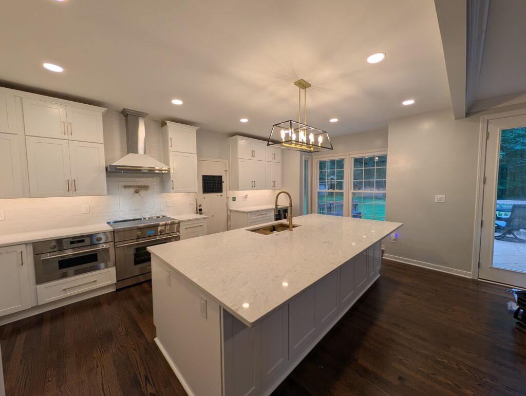 Finished white shaker kitchen with a quartz island, brass lantern and pro range in Rockville, MD