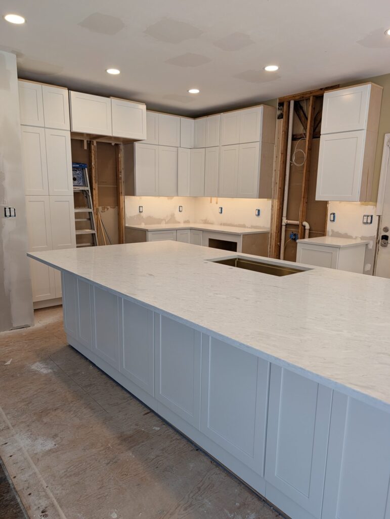 Quartz countertop set on the new island, with white shaker perimeter cabinets and floor-to-ceiling pantry in place.