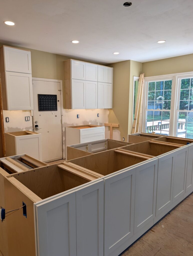 White shaker wall cabinets installed and the new island boxes framed out during installation.