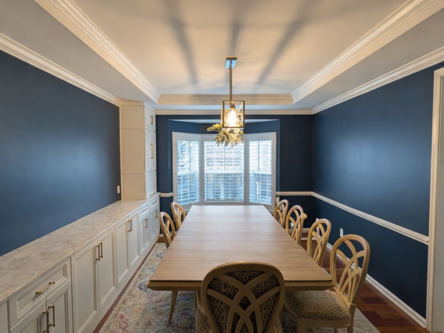 Navy dining room with white built-in base cabinetry along both walls and a long wood dining table