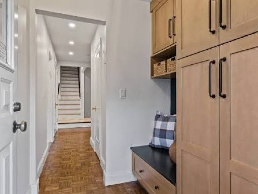 Mudroom entry with light wood lockers, a bench with a plaid cushion and woven storage baskets