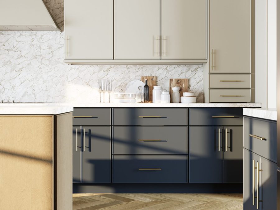 Kitchen detail with cream upper cabinets, navy lower cabinets, marble backsplash and brass hardware